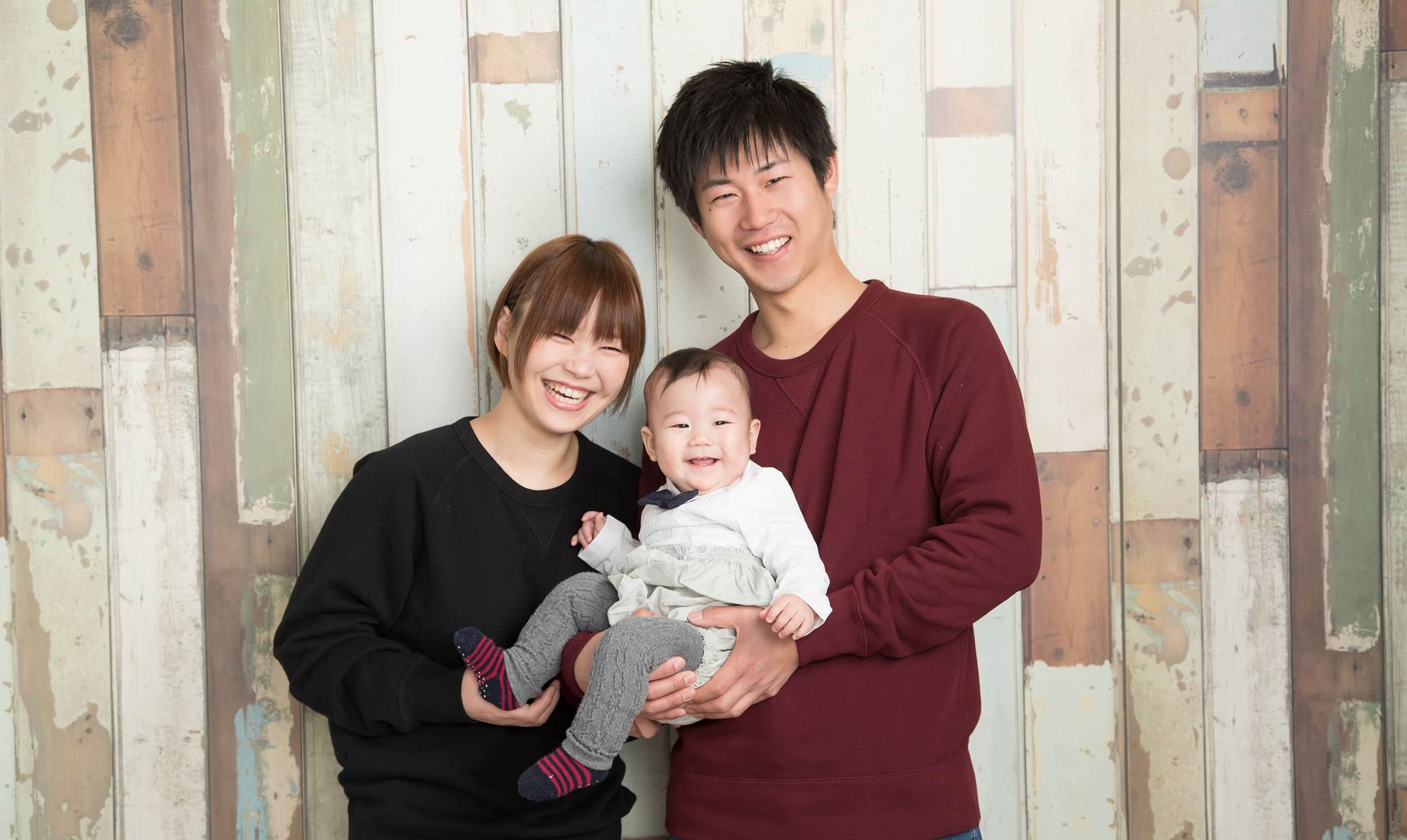 家族写真：赤ちゃんを抱っこして、笑顔の新米ママとパパの写真