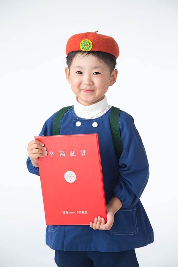 幼稚園卒園写真：幼稚園の制服を着て卒園証書を持っている男の子