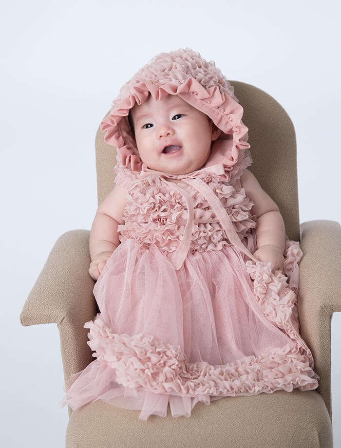 ピンクのベビードレスを着た赤ちゃん写真