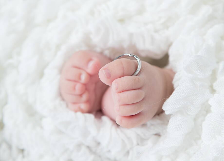 結婚指輪を親指にはめた赤ちゃんの足の写真