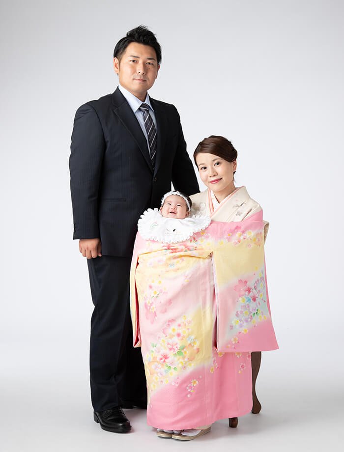 お宮参り祝いで、掛け衣裳を着た赤ちゃんとお母さん・お父さんの写真