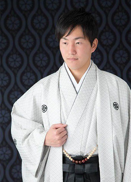成人式撮影:黒い和柄の背景に、羽織袴を着た成人男性の写真
