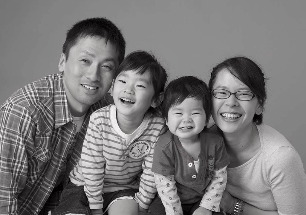 親子4人の家族写真：笑顔で顔を寄せ合っている